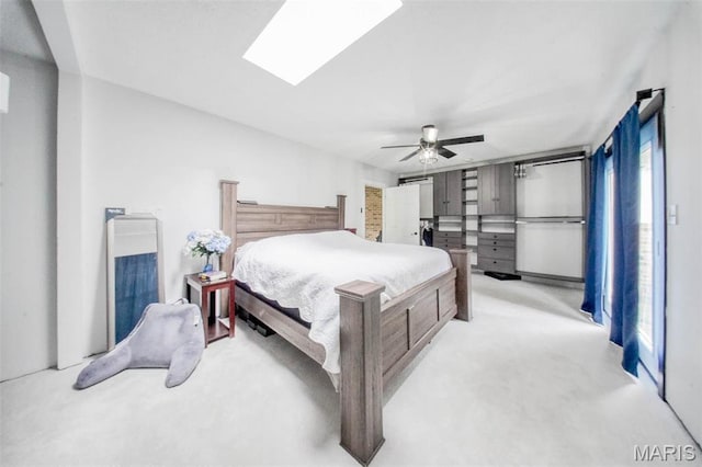 bedroom with light colored carpet, multiple windows, a skylight, and a ceiling fan