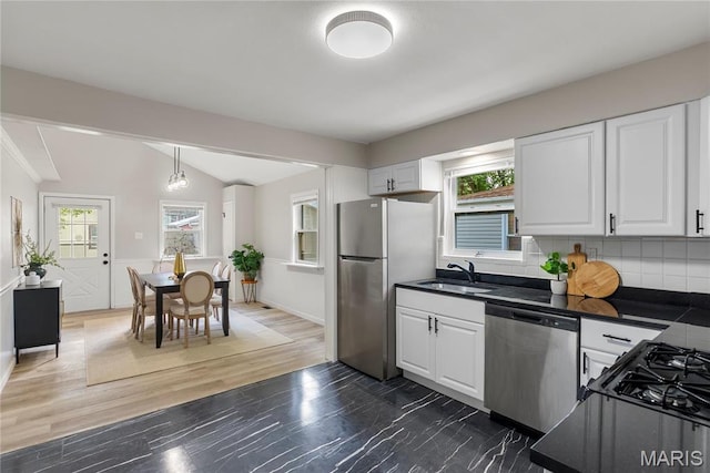 312 Waller Ave, Saint Louis, MO 63125 - kitchen with appliances with stainless steel finishes, a sink, dark countertops, vaulted ceiling, and white cabinetry
