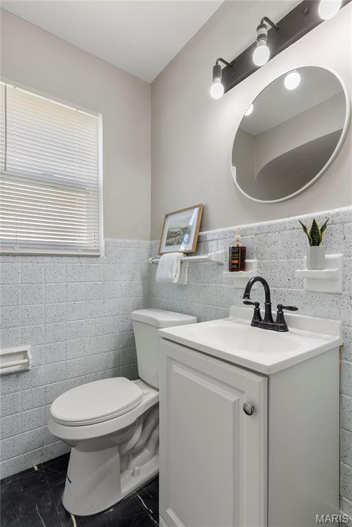 312 Waller Ave, Saint Louis, MO 63125 - half bathroom featuring tile walls, toilet, vanity, wainscoting, and tile patterned flooring