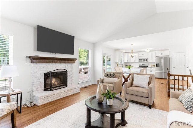 living room with healthy amount of natural light, light wood-type flooring, vaulted ceiling, and a fireplace