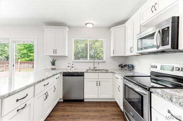 kitchen with appliances with stainless steel finishes, a sink, healthy amount of natural light, and white cabinets