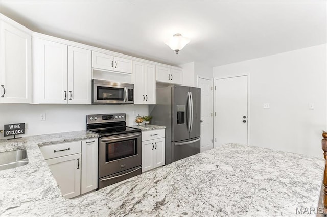 kitchen with appliances with stainless steel finishes, white cabinetry, light stone countertops, and a sink