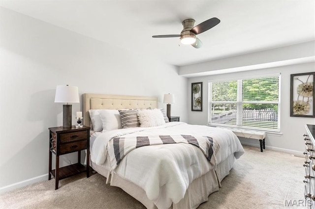 bedroom featuring light colored carpet, baseboards, and a ceiling fan