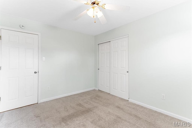 unfurnished bedroom featuring carpet, baseboards, a closet, and a ceiling fan