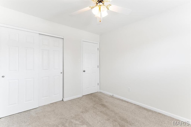 unfurnished bedroom featuring carpet, baseboards, a closet, and a ceiling fan