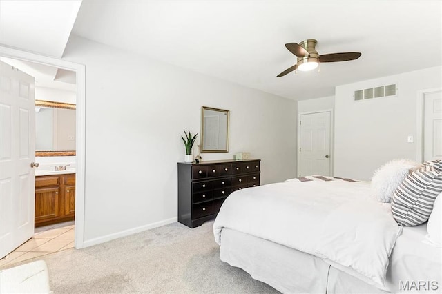 bedroom featuring light colored carpet, ensuite bathroom, baseboards, ceiling fan, and a sink