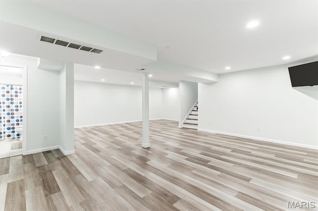 finished below grade area with light wood-type flooring, recessed lighting, stairs, and baseboards