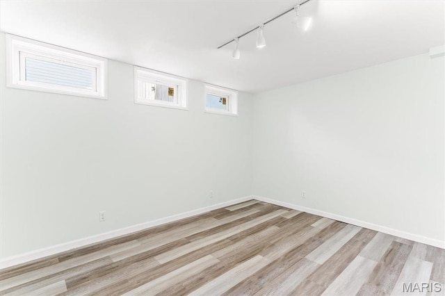 basement with track lighting, light wood-type flooring, and baseboards