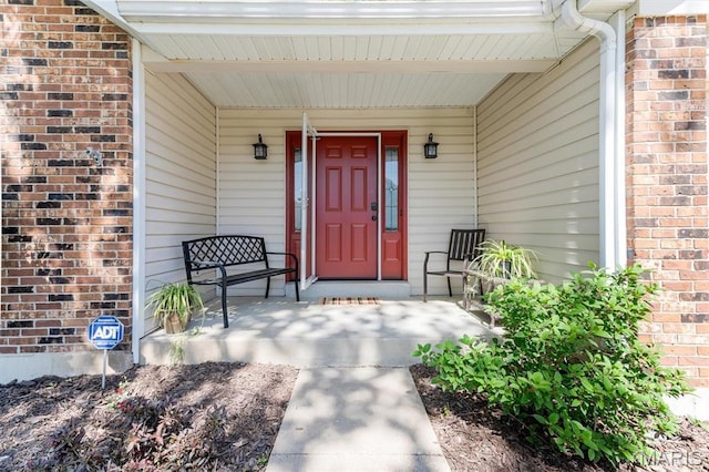 property entrance featuring brick siding and a porch