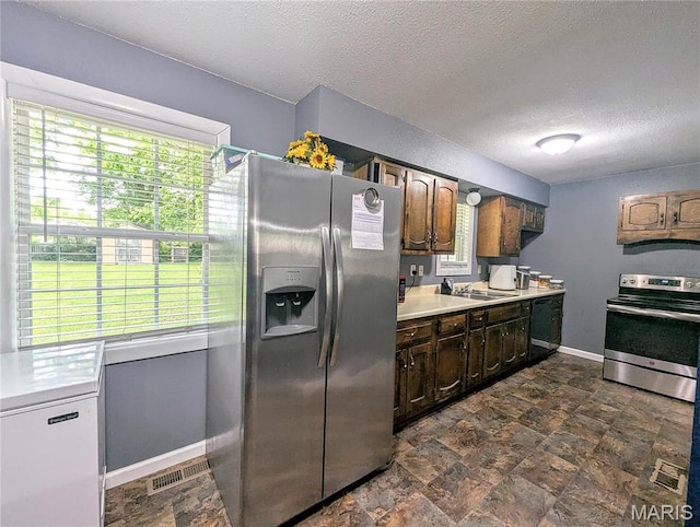 631 W Victor St, Poplar Bluff, MO 63901 - kitchen with appliances with stainless steel finishes, light countertops, a sink, a textured ceiling, and baseboards