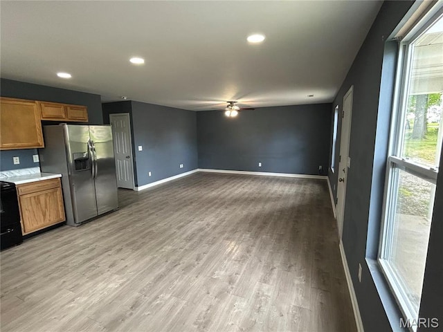 kitchen with stainless steel refrigerator with ice dispenser, ceiling fan, brown cabinetry, baseboards, and light wood-style floors