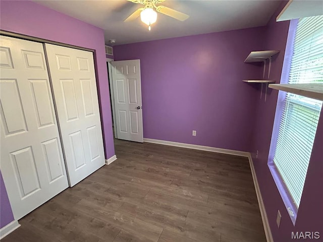 unfurnished bedroom with baseboards, a closet, wood finished floors, and ceiling fan