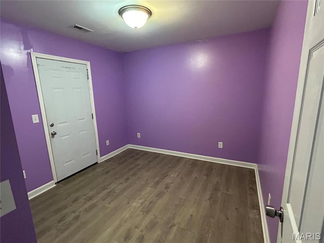unfurnished room featuring dark wood-type flooring and baseboards
