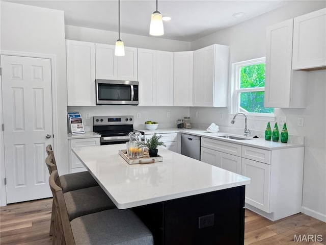 3304 Nat View Ct, Washington, MO 63090 - kitchen featuring stainless steel appliances, a sink, light wood-type flooring, a breakfast bar area, and white cabinetry