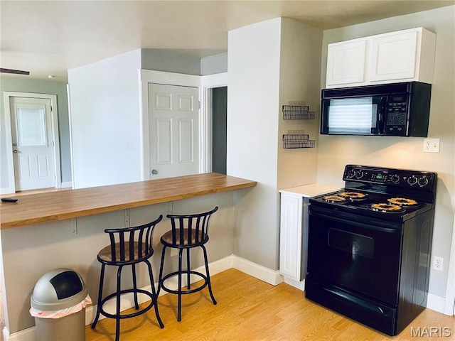 219 2nd St, Winfield, MO 63389 - kitchen featuring black appliances, light wood finished floors, wooden counters, white cabinets, and a breakfast bar