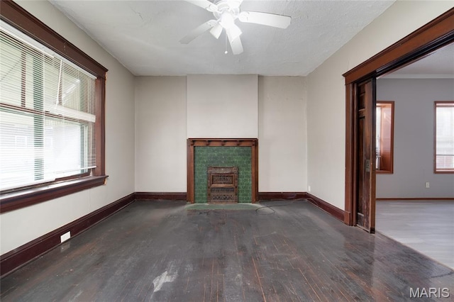 4210 E Carter Ave, Saint Louis, MO 63115 - unfurnished living room featuring wood finished floors, baseboards, a ceiling fan, and a tile fireplace