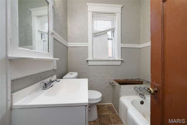 4210 E Carter Ave, Saint Louis, MO 63115 - bathroom with toilet, a garden tub, vanity, a textured wall, and baseboards