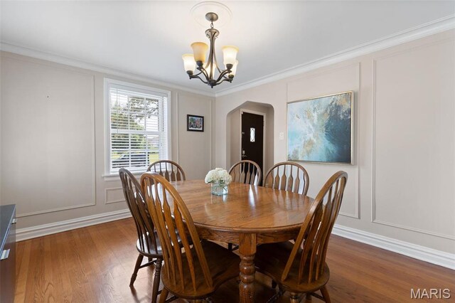 7487 Shaftesbury Ave, University City, MO 63130 - dining space with arched walkways, a decorative wall, a chandelier, dark wood-style flooring, and ornamental molding