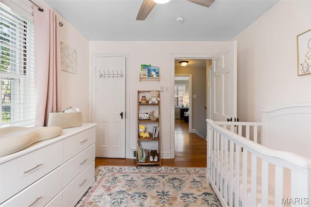 7487 Shaftesbury Ave, University City, MO 63130 - bedroom with light wood-style floors, a crib, and a ceiling fan