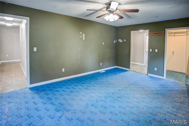 carpeted spare room featuring a ceiling fan and baseboards