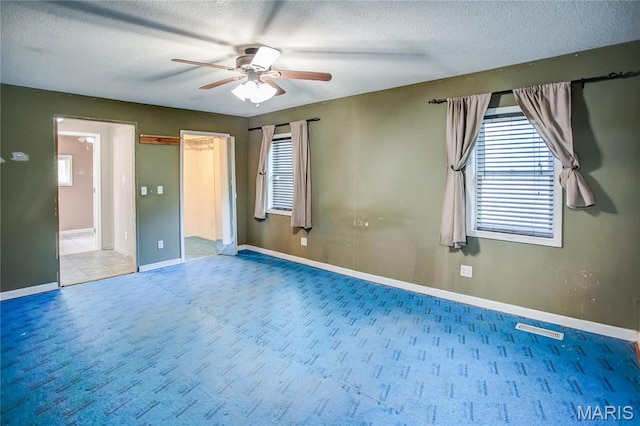 unfurnished bedroom featuring carpet floors, a textured ceiling, baseboards, and a ceiling fan