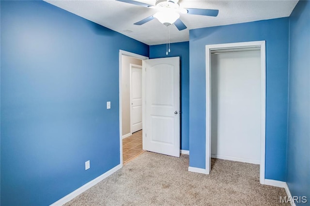 unfurnished bedroom featuring carpet flooring, baseboards, a closet, and a ceiling fan