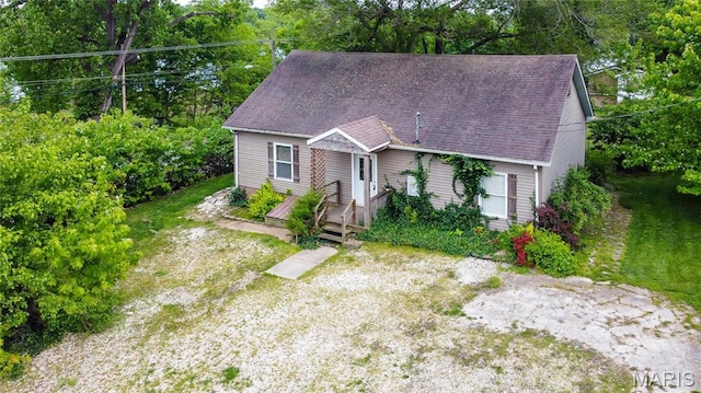 view of front of property with view of scattered trees and a shingled roof