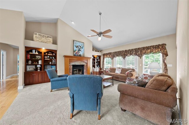 living room featuring high vaulted ceiling, a brick fireplace, ceiling fan, built in shelves, and wood finished floors