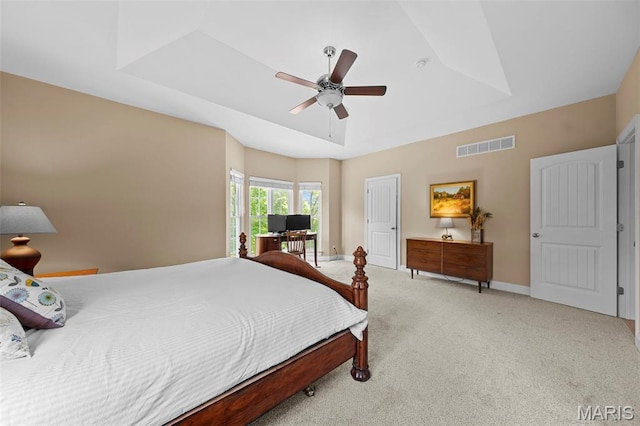 bedroom featuring light colored carpet, a raised ceiling, a ceiling fan, and baseboards