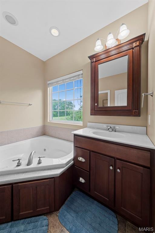 bathroom with a jetted tub, tile patterned floors, and vanity