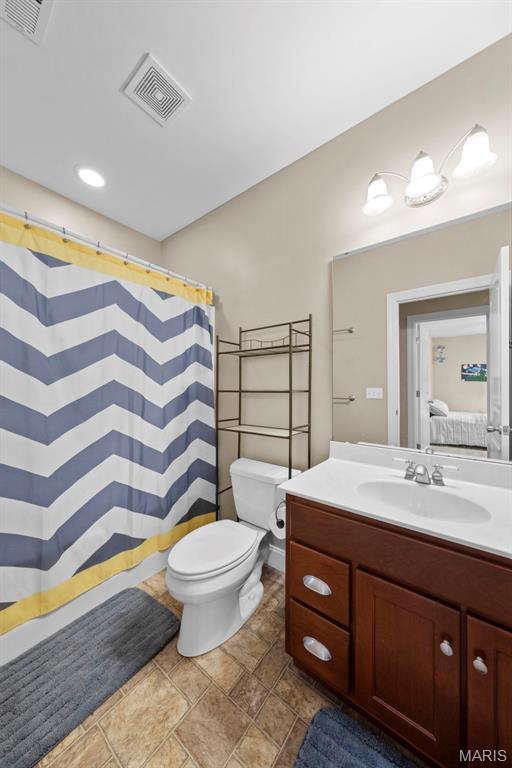 full bath with toilet, vanity, stone finish flooring, and a shower with curtain