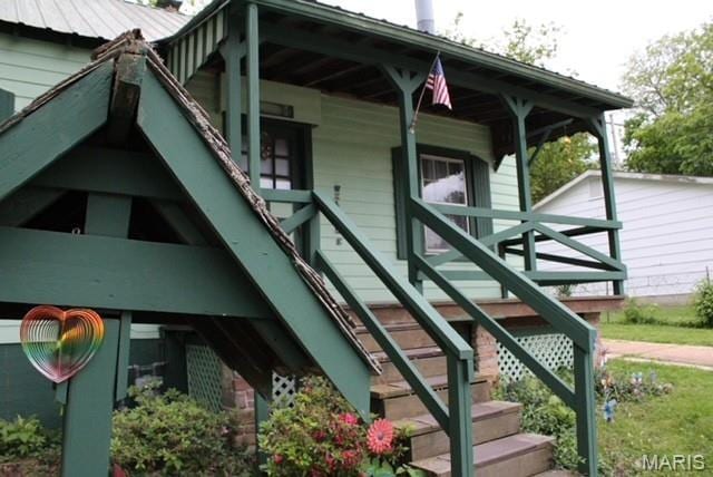 view of side of property featuring stairs and covered porch