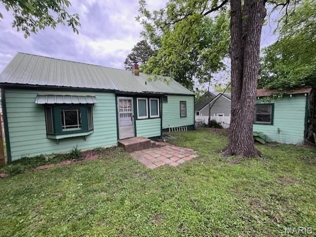 back of property with a yard and metal roof