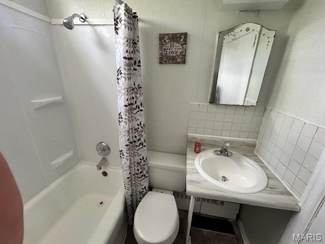bathroom featuring a sink, shower / bath combination with curtain, toilet, and backsplash
