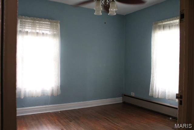 spare room with baseboard heating, a ceiling fan, baseboards, and wood finished floors