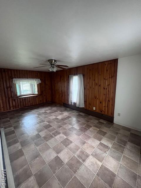 empty room featuring wood walls and a ceiling fan