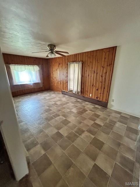 spare room featuring ceiling fan, wooden walls, and tile patterned floors