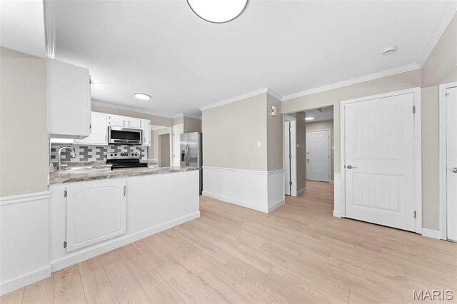 3009 Country Knoll Dr, Saint Charles, MO 63303 - kitchen with appliances with stainless steel finishes, a peninsula, backsplash, light wood-type flooring, and crown molding