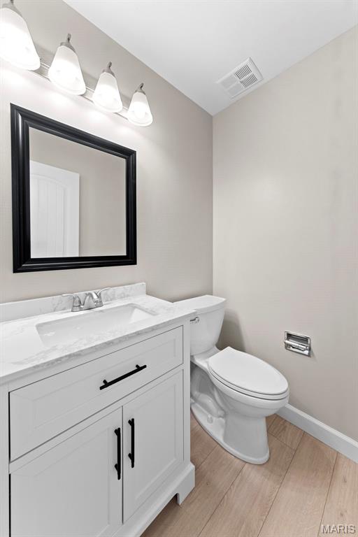 3009 Country Knoll Dr, Saint Charles, MO 63303 - bathroom with wood finished floors, toilet, vanity, and baseboards