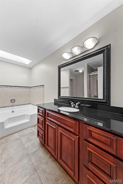 3009 Country Knoll Dr, Saint Charles, MO 63303 - bathroom featuring a skylight, a bath, vanity, tile patterned flooring, and a shower with door