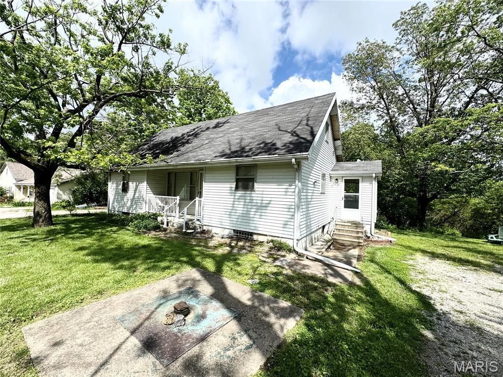 view of front of house featuring entry steps, a front yard, a shingled roof, and an outdoor fire pit