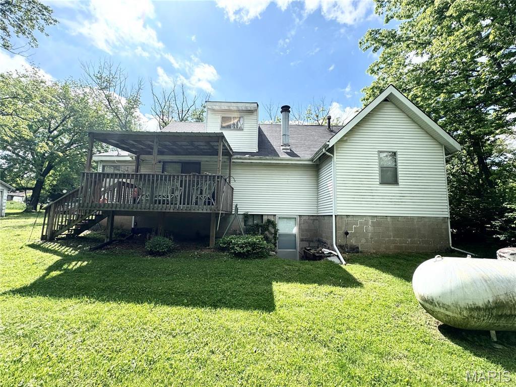 rear view of property with a wooden deck, a lawn, stairway, and a shingled roof