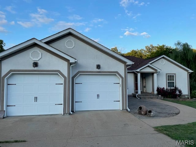 ranch-style house featuring concrete driveway, stucco siding, and a garage