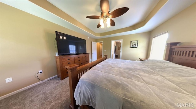 bedroom featuring carpet floors, baseboards, a tray ceiling, and ceiling fan