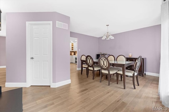 dining room featuring a chandelier, light wood finished floors, and baseboards