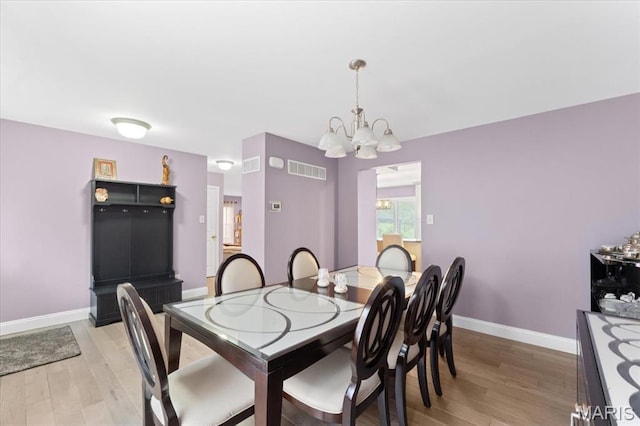 dining room featuring a chandelier, light wood-type flooring, and baseboards