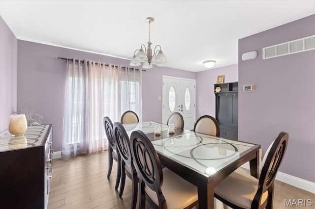 dining space with a chandelier, light wood-style flooring, and baseboards