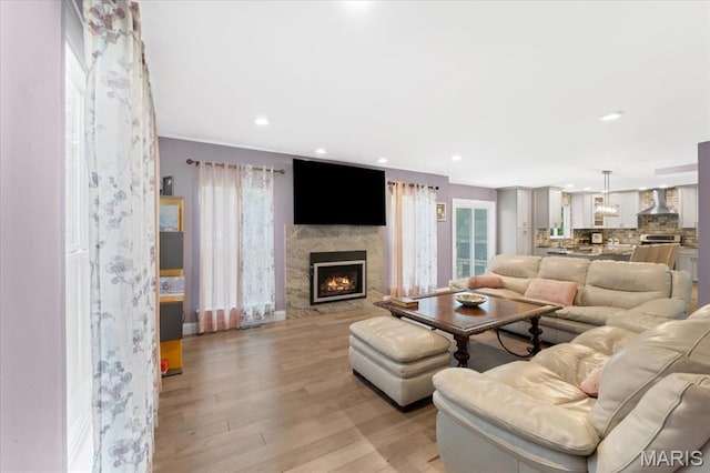 living room featuring light wood-type flooring, a lit fireplace, and recessed lighting