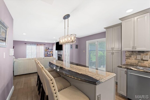 kitchen featuring stainless steel dishwasher, plenty of natural light, decorative backsplash, dark stone countertops, and recessed lighting