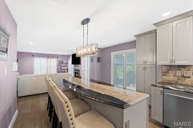 kitchen featuring stainless steel dishwasher, plenty of natural light, backsplash, dark stone counters, and recessed lighting